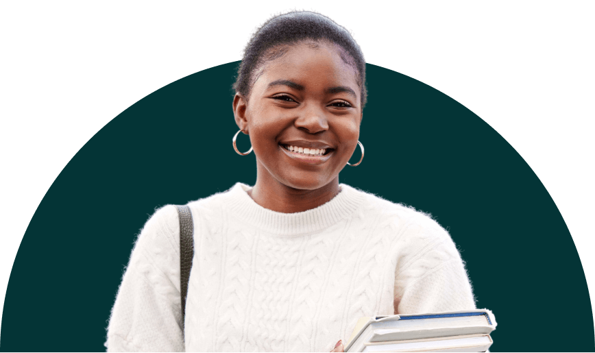 A smiling student carrying a stack of books in her arms