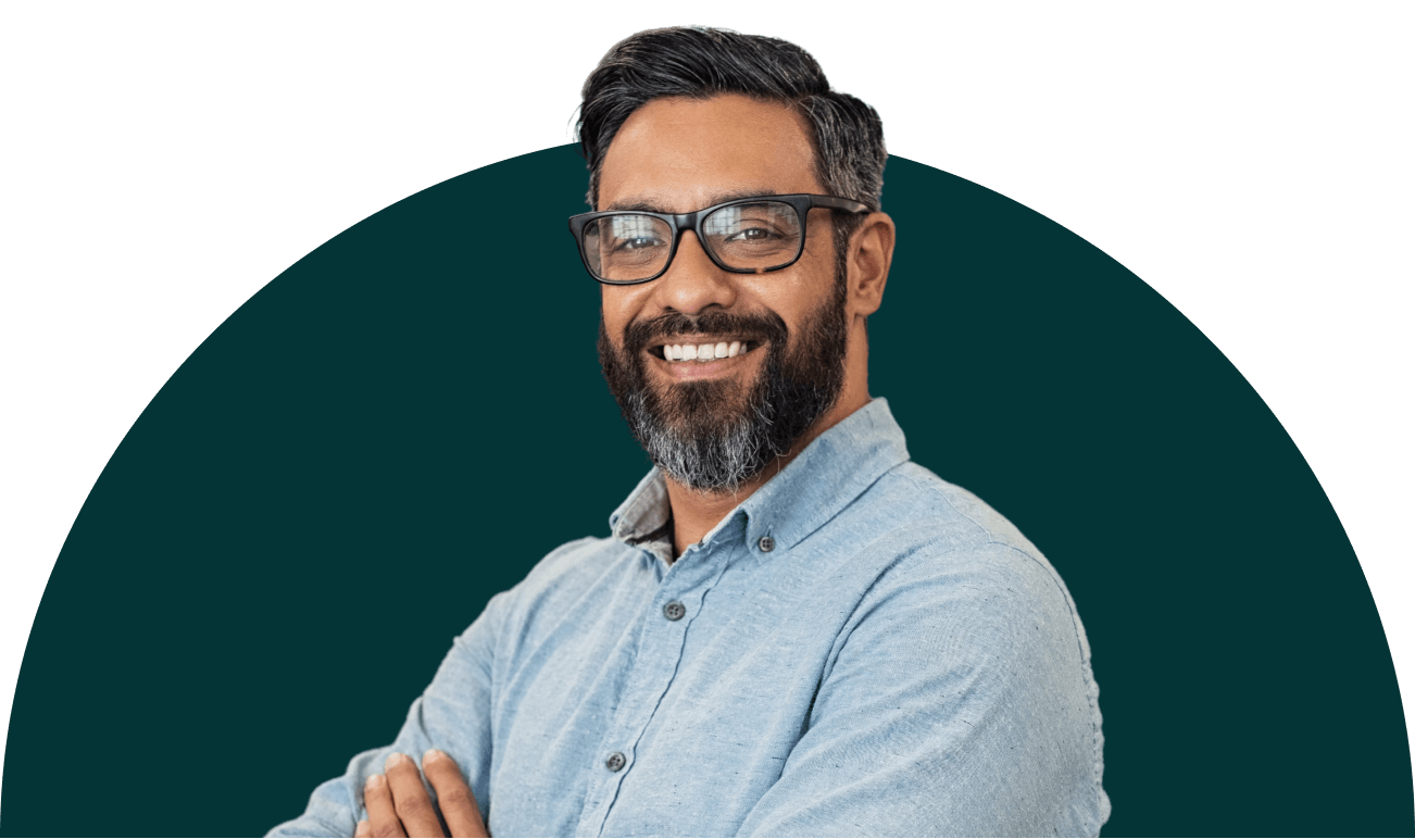 A smiling man with glasses and a beard who is standing with his arms crossed in a relaxed manner